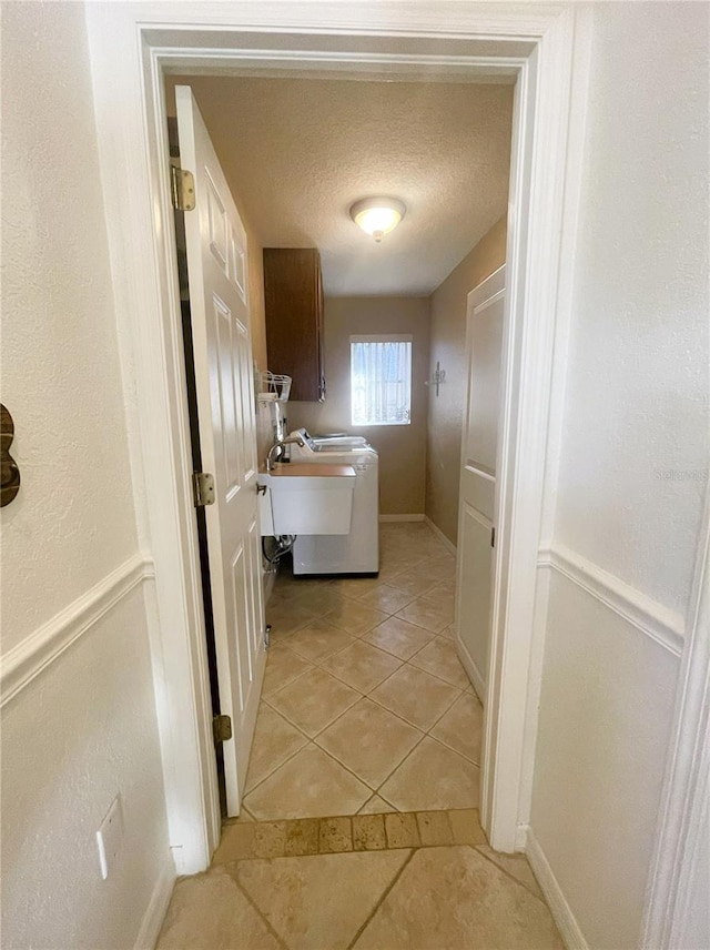 washroom with cabinets, light tile patterned floors, a textured ceiling, and washer / dryer