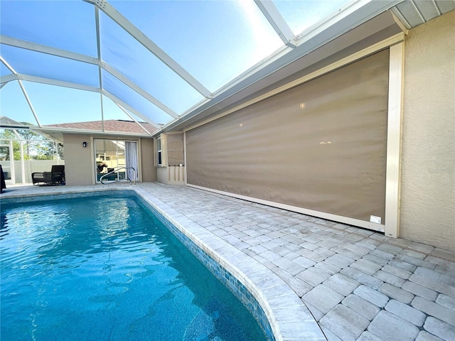 view of pool with glass enclosure and a patio