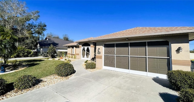 view of front of home with a garage, concrete driveway, a front lawn, and stucco siding