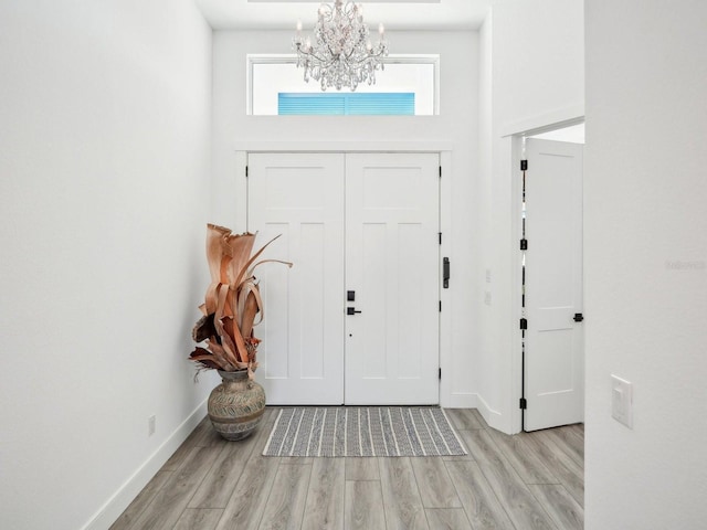 foyer entrance with light hardwood / wood-style floors and a chandelier