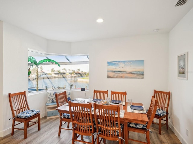 dining area with hardwood / wood-style floors and a water view