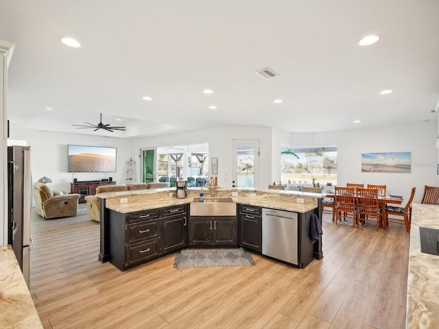 kitchen featuring light stone countertops, light wood-type flooring, stainless steel appliances, ceiling fan, and sink