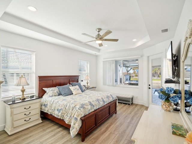 bedroom featuring access to outside, a raised ceiling, ceiling fan, and multiple windows