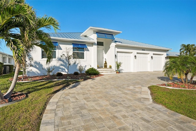 view of front of home with a garage, a front yard, and central air condition unit