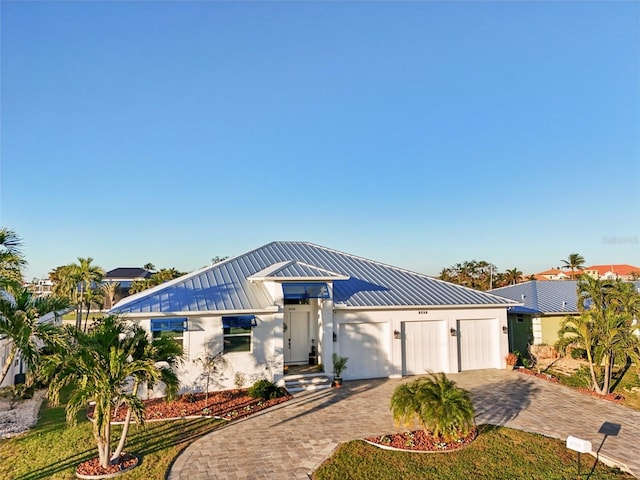 view of front facade with stucco siding, decorative driveway, an attached garage, and metal roof