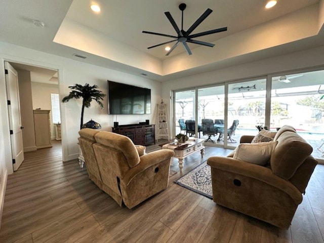 living area featuring wood finished floors, recessed lighting, a ceiling fan, and a raised ceiling