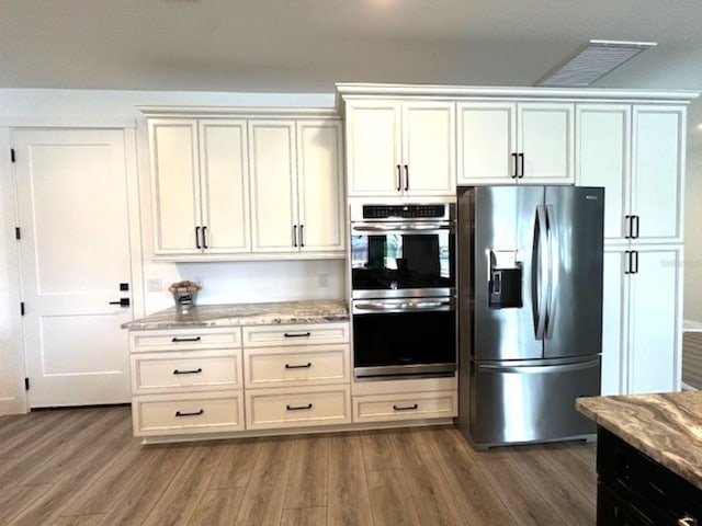 kitchen featuring dark wood finished floors, light stone countertops, visible vents, and appliances with stainless steel finishes