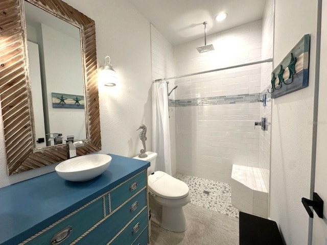 bathroom with tiled shower, toilet, and vanity