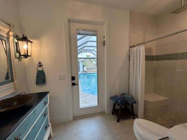 full bathroom featuring toilet, tiled shower, tile patterned flooring, baseboards, and vanity