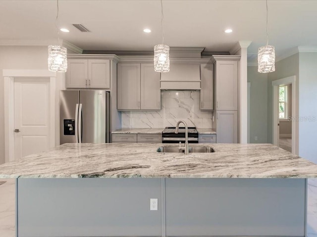 kitchen featuring light stone countertops, stainless steel fridge, pendant lighting, gray cabinets, and decorative backsplash