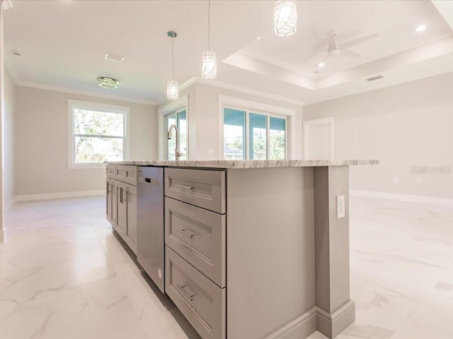 kitchen featuring ceiling fan, a tray ceiling, decorative light fixtures, a kitchen island, and light stone counters