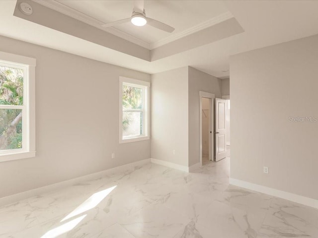 empty room with ceiling fan, a raised ceiling, and ornamental molding