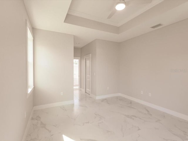 spare room with a raised ceiling, ceiling fan, crown molding, and a healthy amount of sunlight