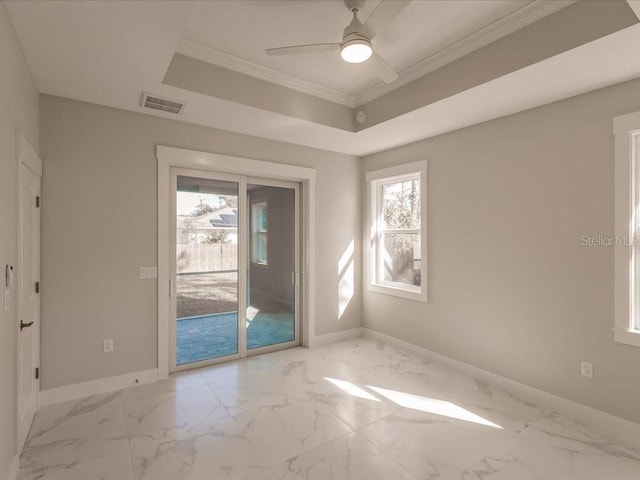 empty room with ceiling fan, a raised ceiling, and crown molding