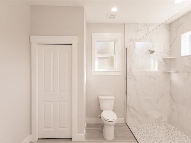 bathroom featuring a tile shower, wood-type flooring, and toilet