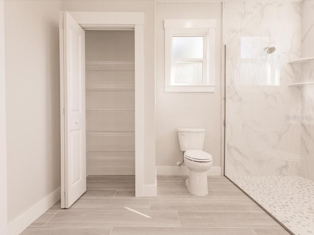 bathroom featuring a tile shower and toilet