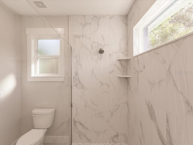 bathroom with a tile shower and toilet