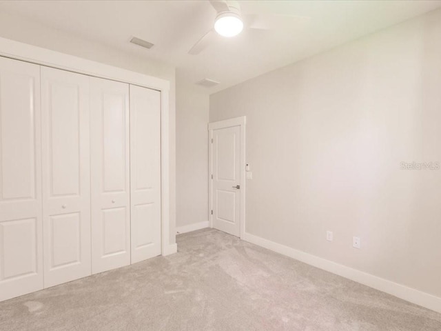 unfurnished bedroom featuring ceiling fan, a closet, and light carpet