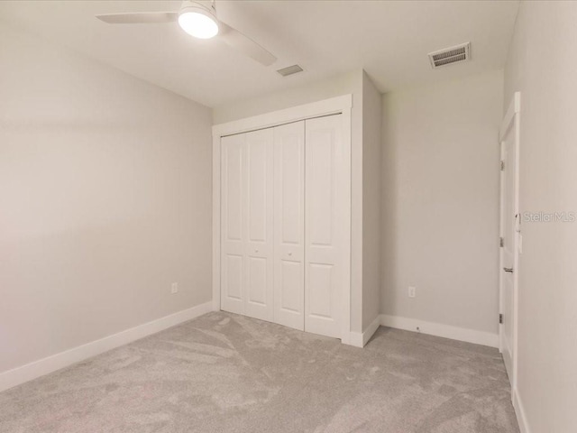 unfurnished bedroom with ceiling fan, a closet, and light colored carpet