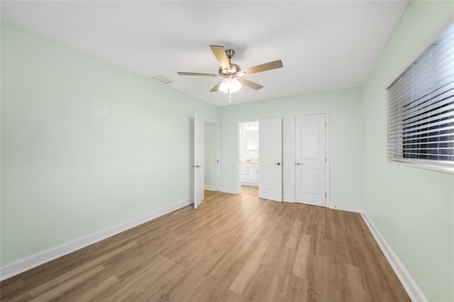 unfurnished bedroom featuring light wood-type flooring, a closet, ensuite bath, and ceiling fan