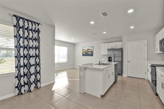 kitchen featuring light tile patterned floors, sink, white cabinetry, stainless steel appliances, and an island with sink