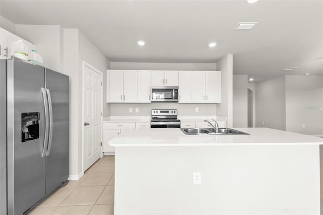 kitchen featuring appliances with stainless steel finishes, sink, white cabinets, light tile patterned floors, and a center island with sink