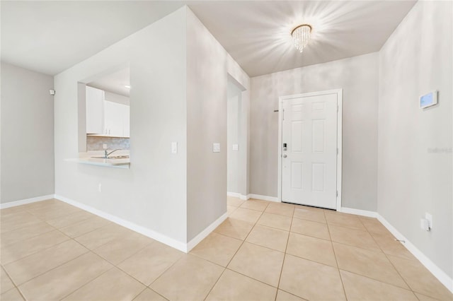 foyer entrance featuring light tile patterned floors, sink, and an inviting chandelier