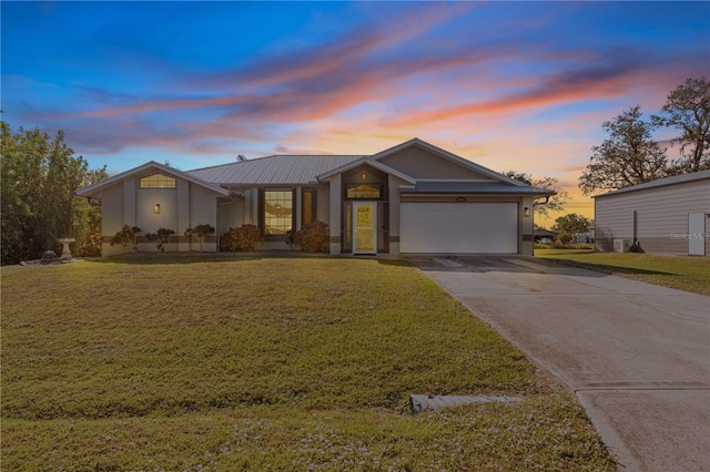 view of front of home with a garage and a lawn