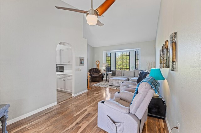 living room featuring ceiling fan, high vaulted ceiling, and light hardwood / wood-style flooring