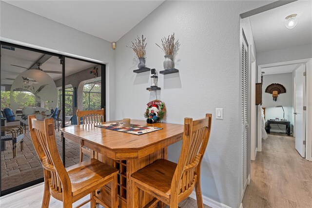 dining area featuring light wood-type flooring and vaulted ceiling