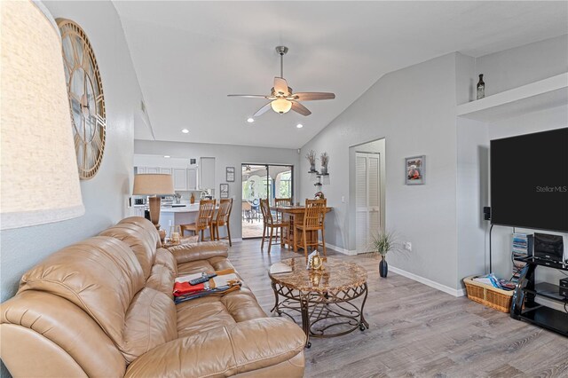 living room with ceiling fan, light hardwood / wood-style floors, and lofted ceiling