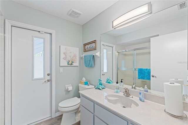 bathroom with vanity, wood-type flooring, an enclosed shower, and toilet