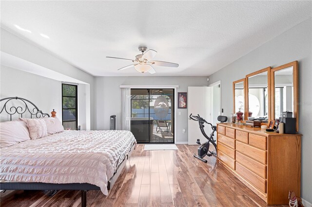 bedroom with access to exterior, ceiling fan, hardwood / wood-style floors, and a textured ceiling