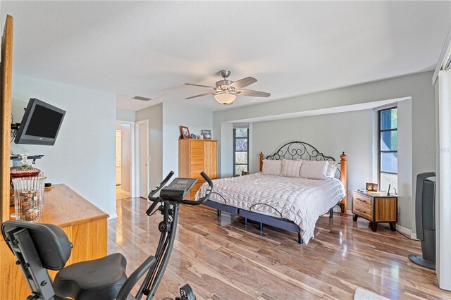 bedroom with hardwood / wood-style flooring, ceiling fan, and multiple windows