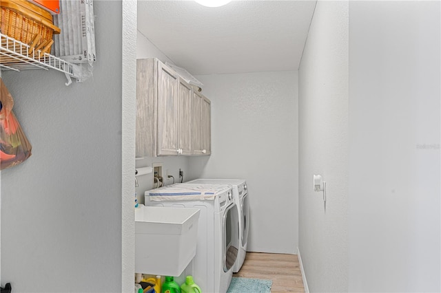 laundry area with cabinets, washing machine and dryer, light hardwood / wood-style flooring, and sink