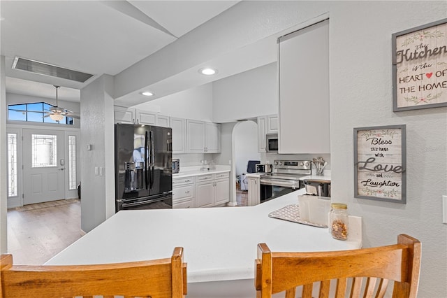 kitchen featuring kitchen peninsula, stainless steel appliances, white cabinetry, and a breakfast bar area