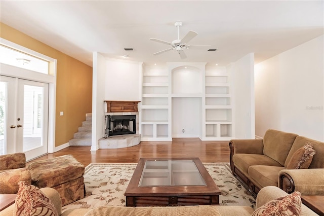 living room featuring french doors, ceiling fan, built in shelves, and wood-type flooring