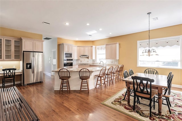 interior space with hanging light fixtures, light stone counters, a chandelier, wood-type flooring, and appliances with stainless steel finishes