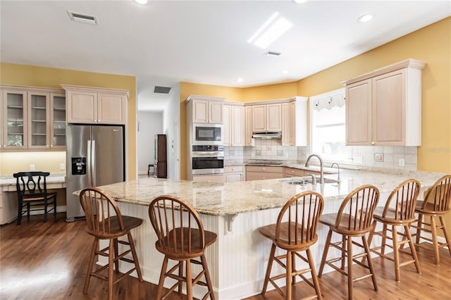 kitchen featuring a kitchen breakfast bar, sink, stainless steel appliances, and dark wood-type flooring