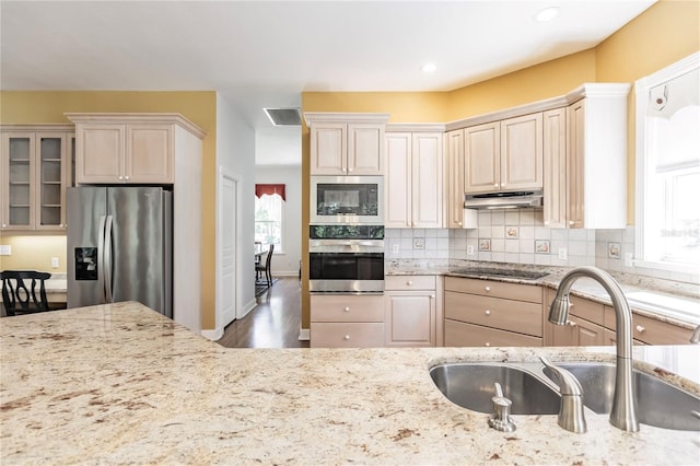 kitchen featuring cream cabinets, sink, decorative backsplash, light stone countertops, and appliances with stainless steel finishes