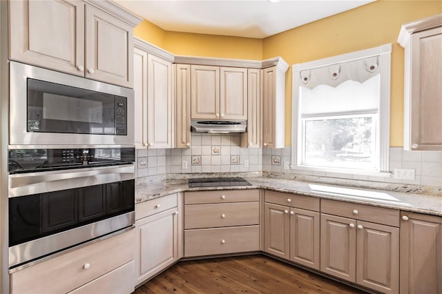 kitchen featuring light stone counters, black electric cooktop, built in microwave, dark wood-type flooring, and oven