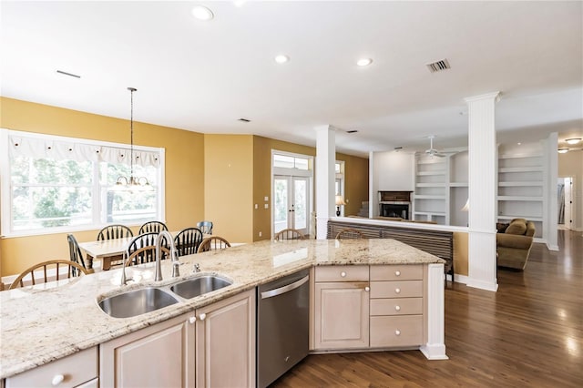 kitchen with dishwasher, sink, light stone counters, built in features, and a breakfast bar area