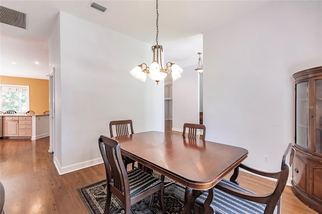 dining space with hardwood / wood-style floors and a notable chandelier