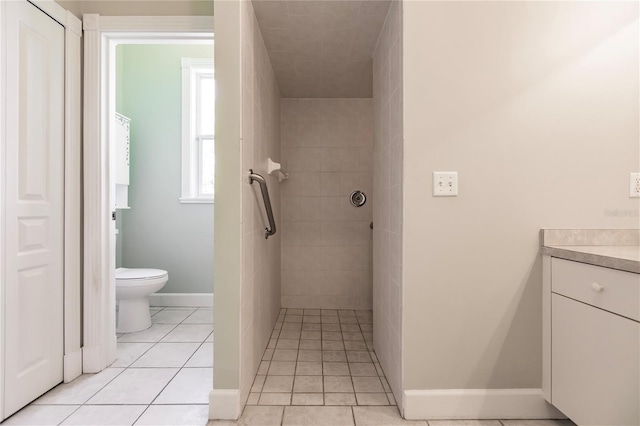 bathroom with tile patterned flooring, vanity, toilet, and tiled shower