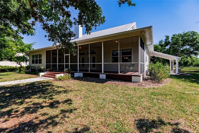 back of house featuring a lawn and a sunroom