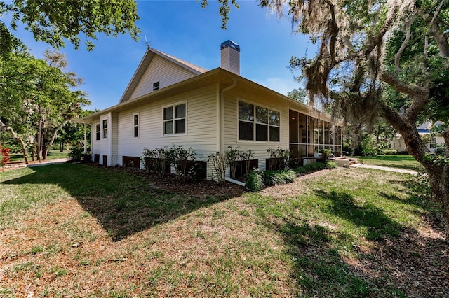 view of home's exterior with a lawn and a sunroom