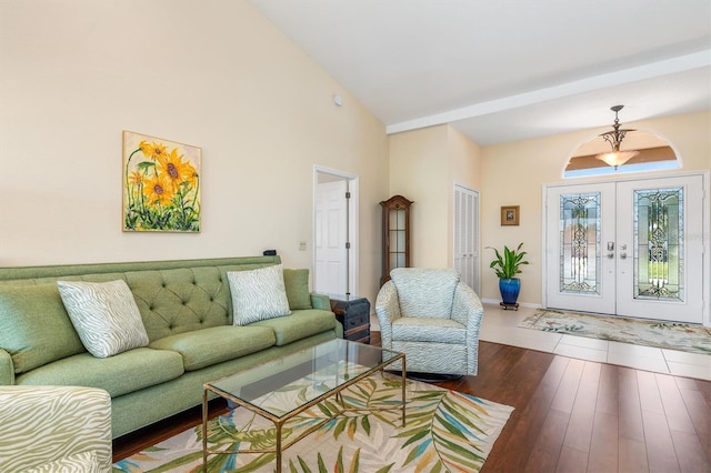 living room with dark hardwood / wood-style floors, high vaulted ceiling, and french doors