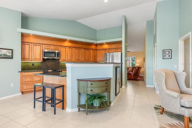 kitchen featuring light tile patterned floors, a breakfast bar area, a kitchen island, decorative backsplash, and vaulted ceiling