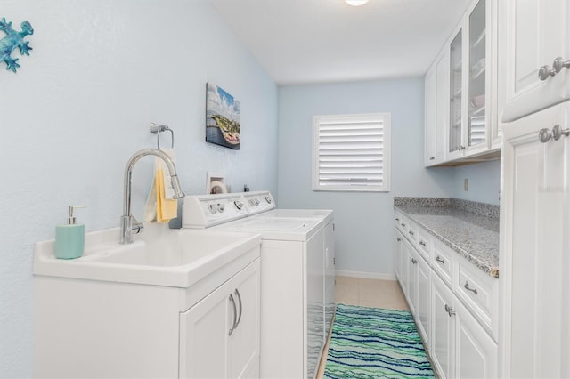 laundry room with cabinets, washing machine and clothes dryer, and light tile patterned floors