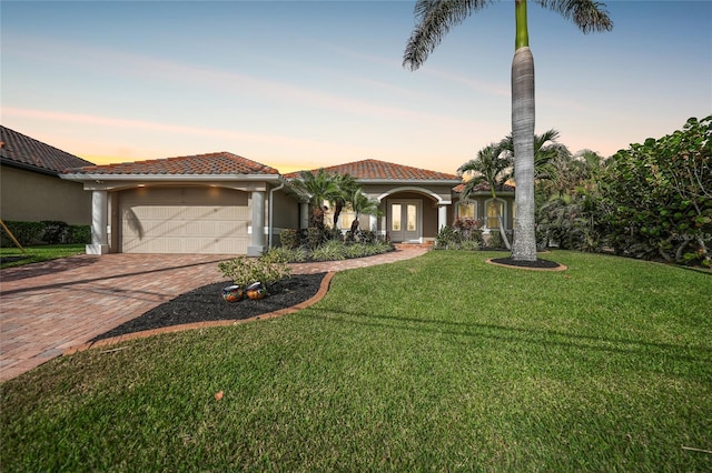 mediterranean / spanish home with a garage, a yard, and french doors